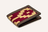 The Travis Heights Wallet by Zilker Belts is a handcrafted leather wallet with a stunning red and beige geometric pattern on the front, featuring unique Argentine woven fabric.