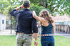 a man and a woman standing in a grassy area wearing Zilker Belts' ATX Dark.